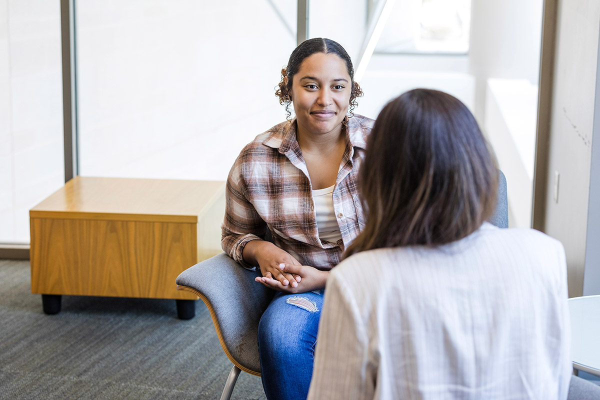 two people sitting face to face, talking in an office