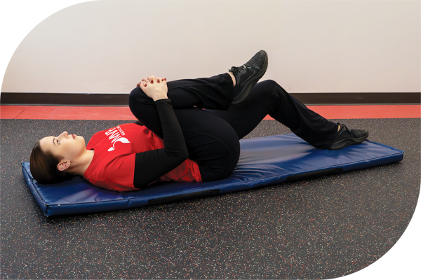 Using both hands, pull up one knee and press it toward your chest. 