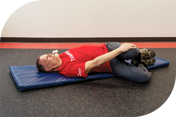Keep your shoulders firmly on the floor and slowly roll your bent knees to one side.