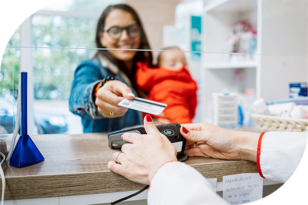 Person holding a baby and presenting a payment card at a healthcare provider's reception desk.