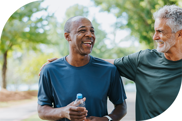 Two men in athletic wear outdoors, one holding a water bottle, showing support and companionship.