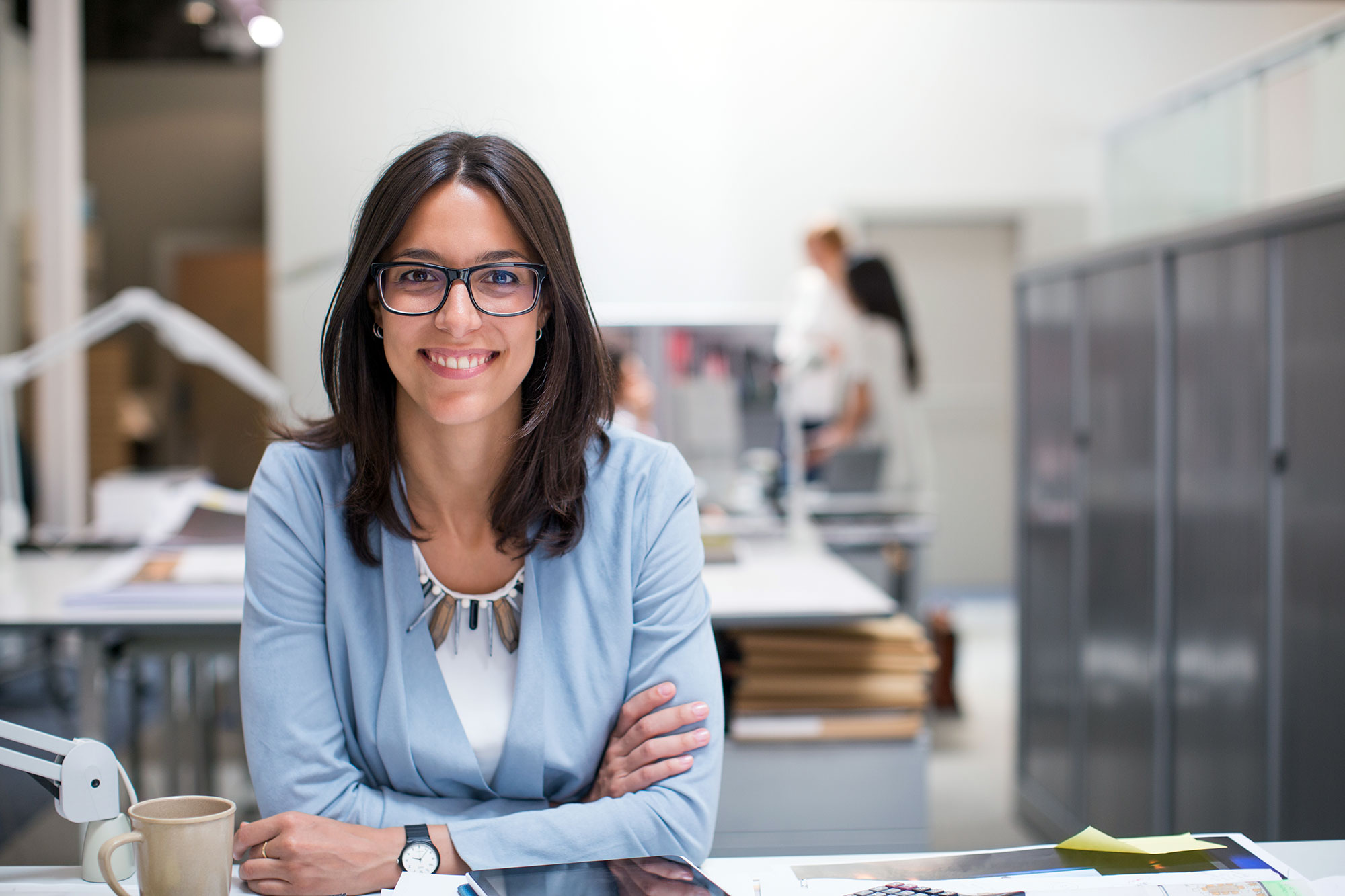 woman wearing glasses sits at a desk in an office