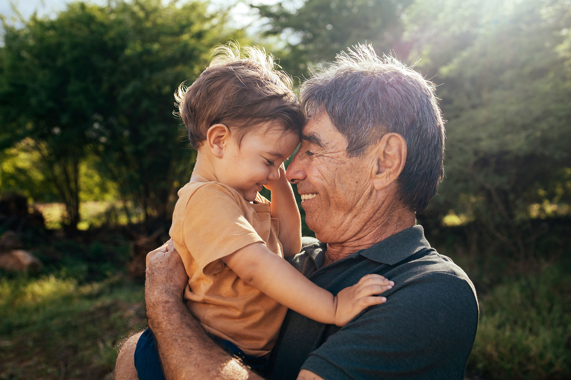 older man hugging a little boy outdoors