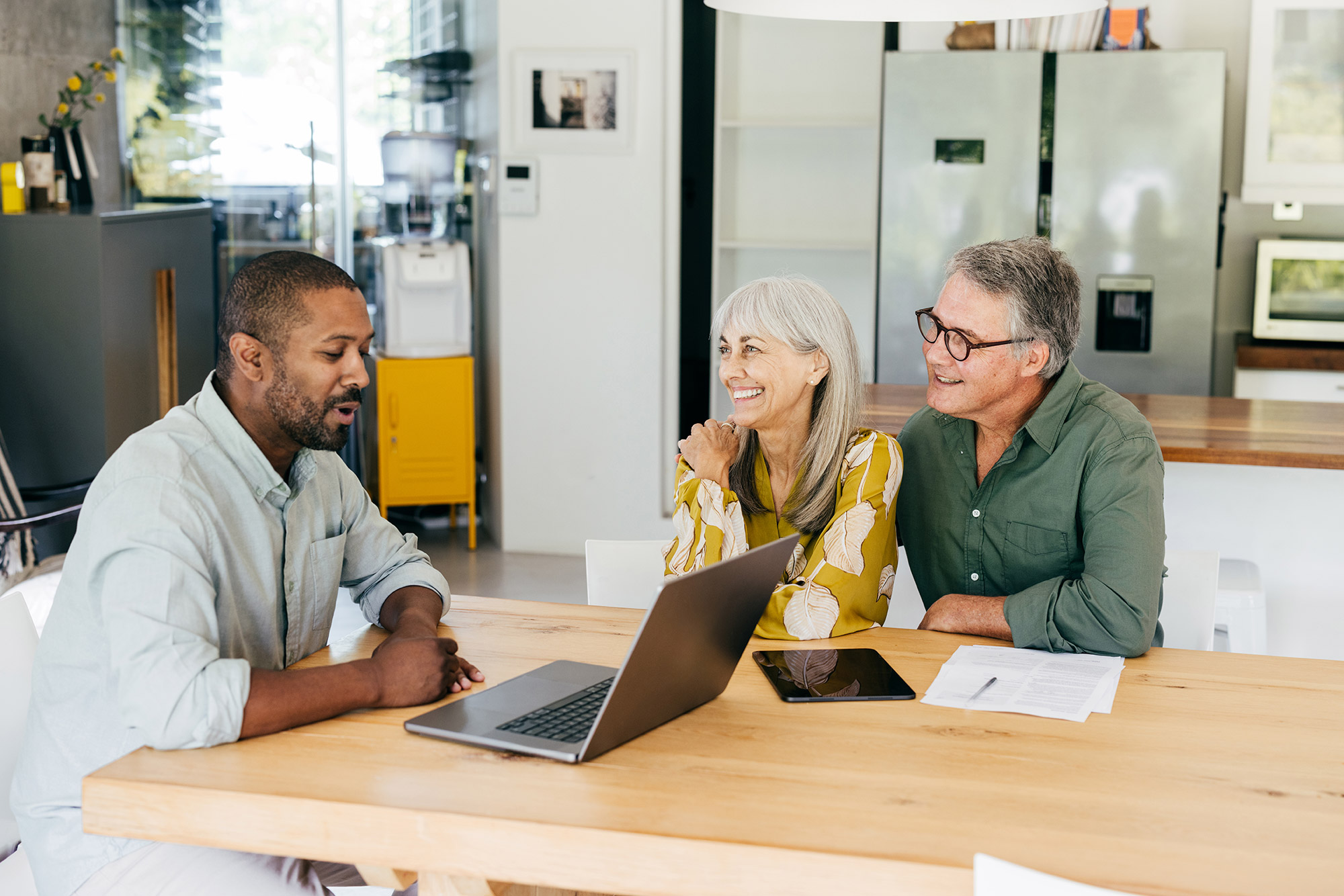 Three people sitting at a table looking at a laptop