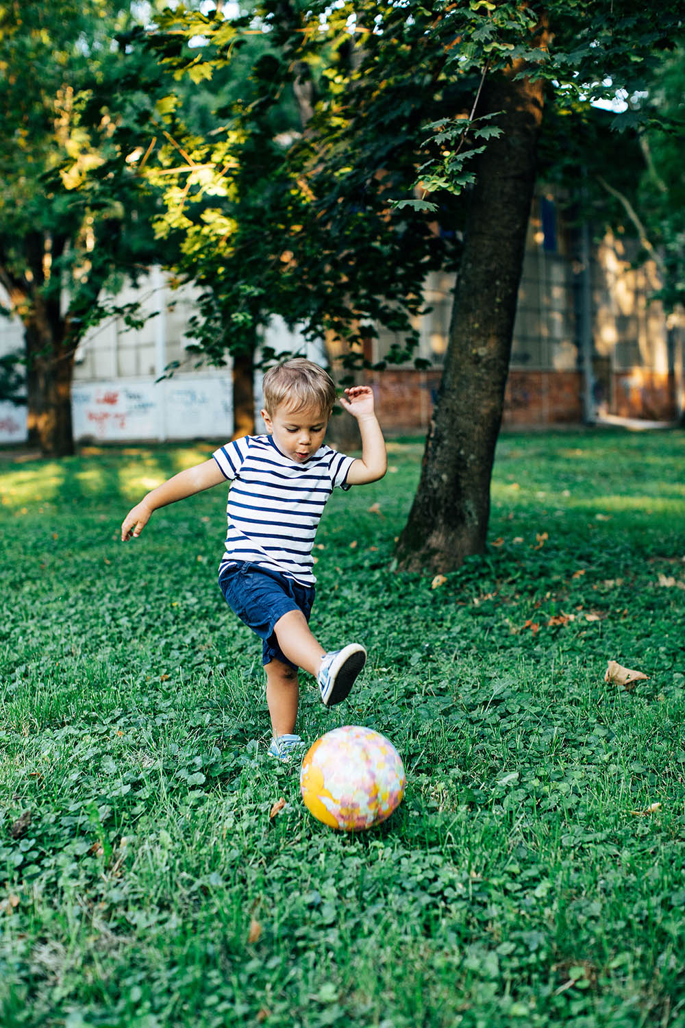 little boy kicking soccer ball in yard