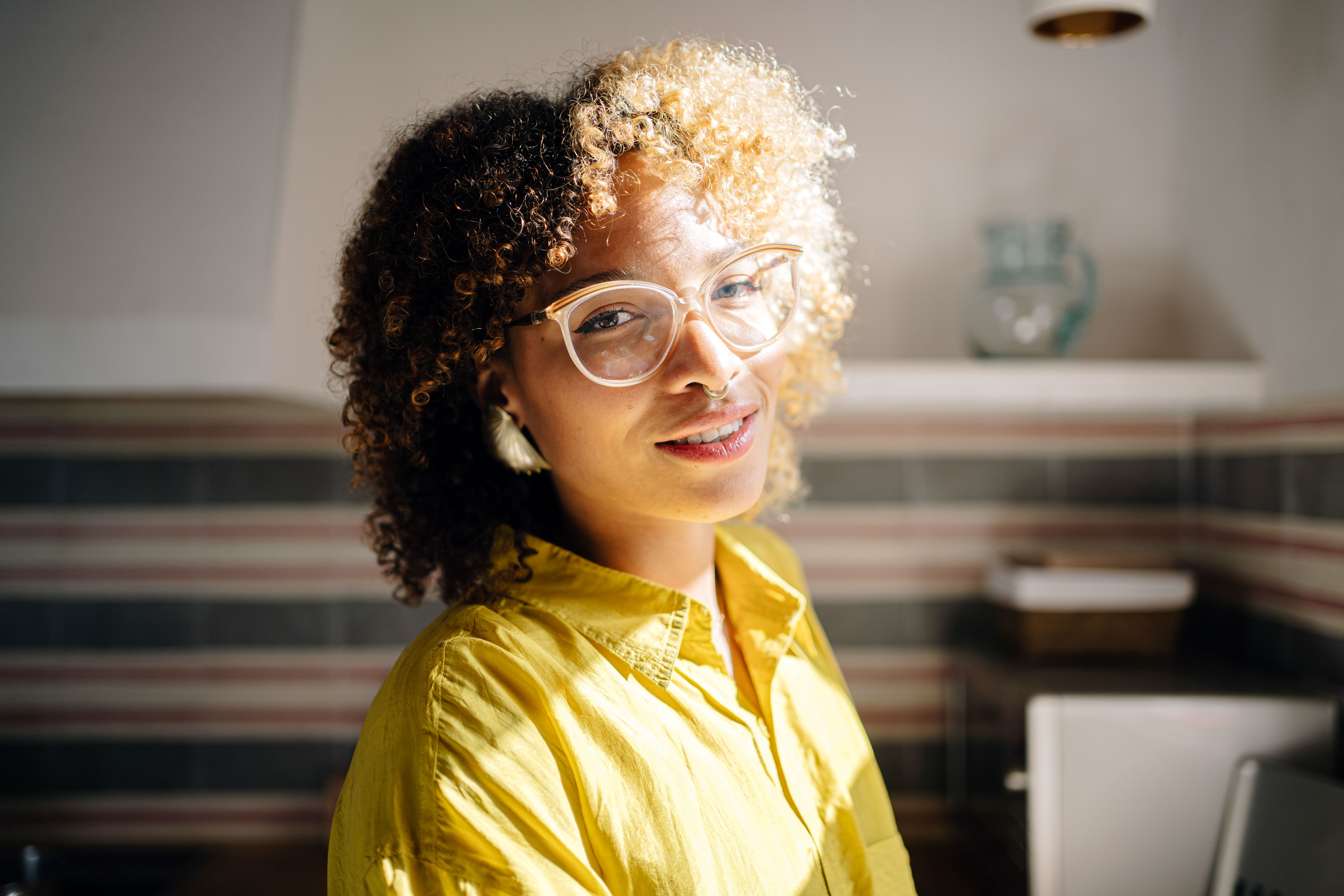 a woman standing indoors with sunlight on her face