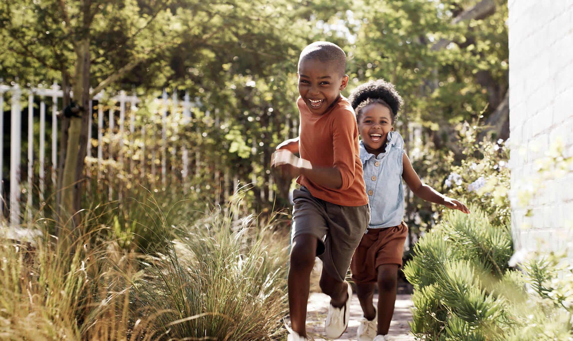 two children running through a green garden