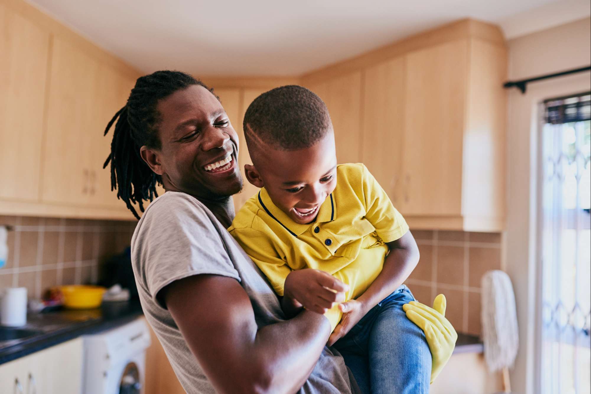 father roughhousing with child in kitchen