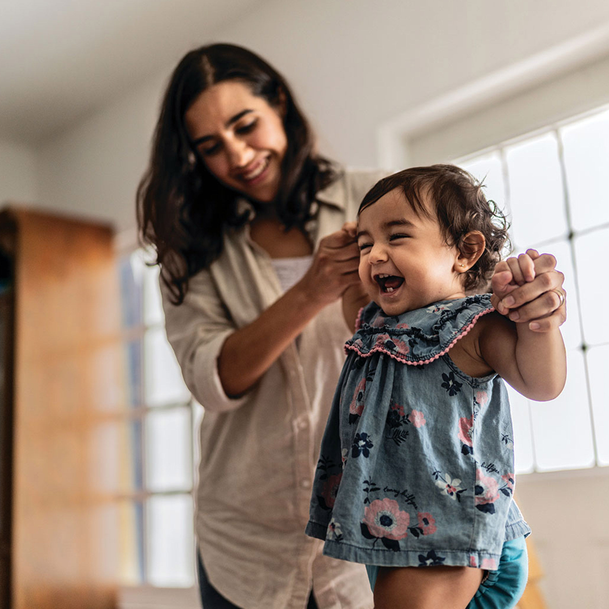 a woman holding a small baby indoors