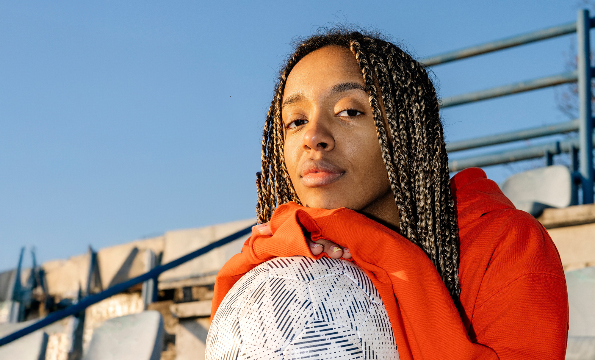 young woman sitting on bleachers with a soccer ball