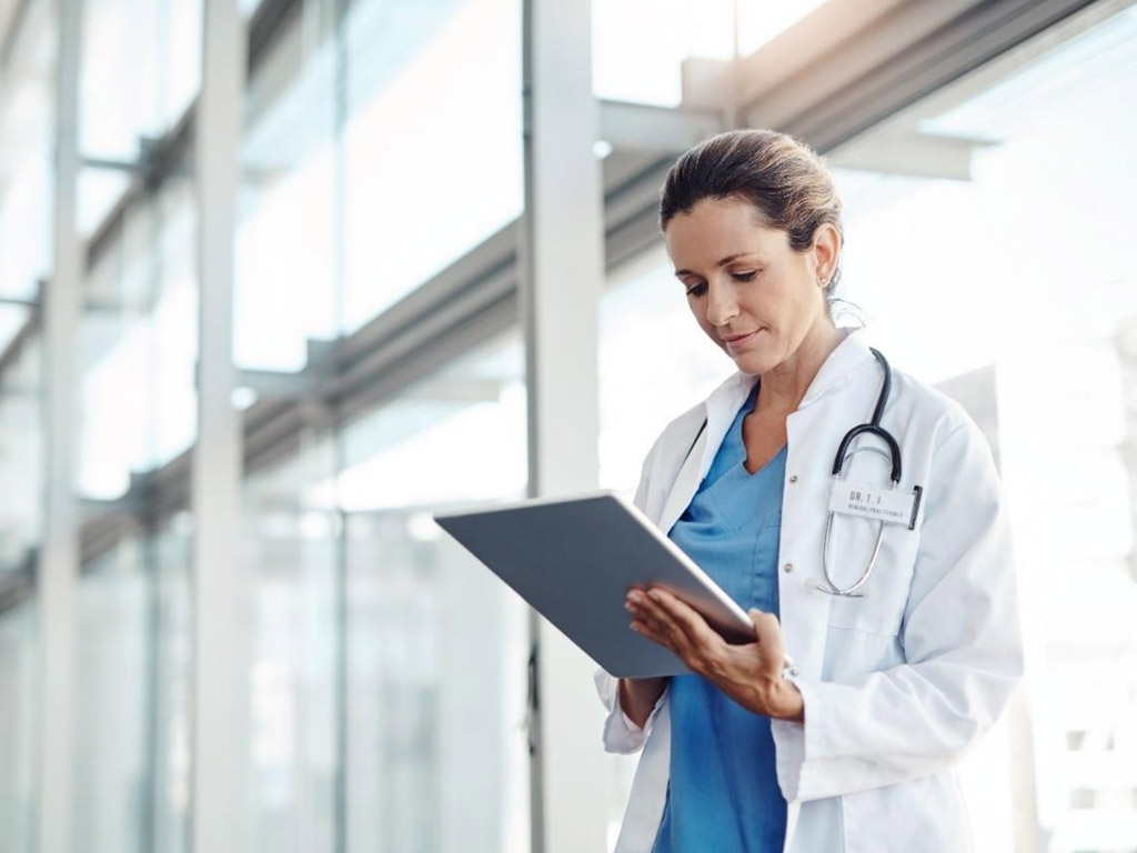 a female doctor in a lab coat holds a tablet