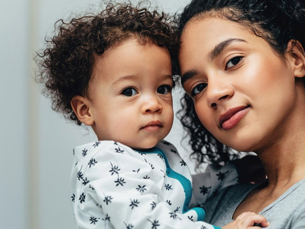 a woman smiles while holding a baby in her arms