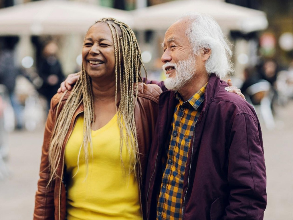 an older couple smiling and standing together outdoors