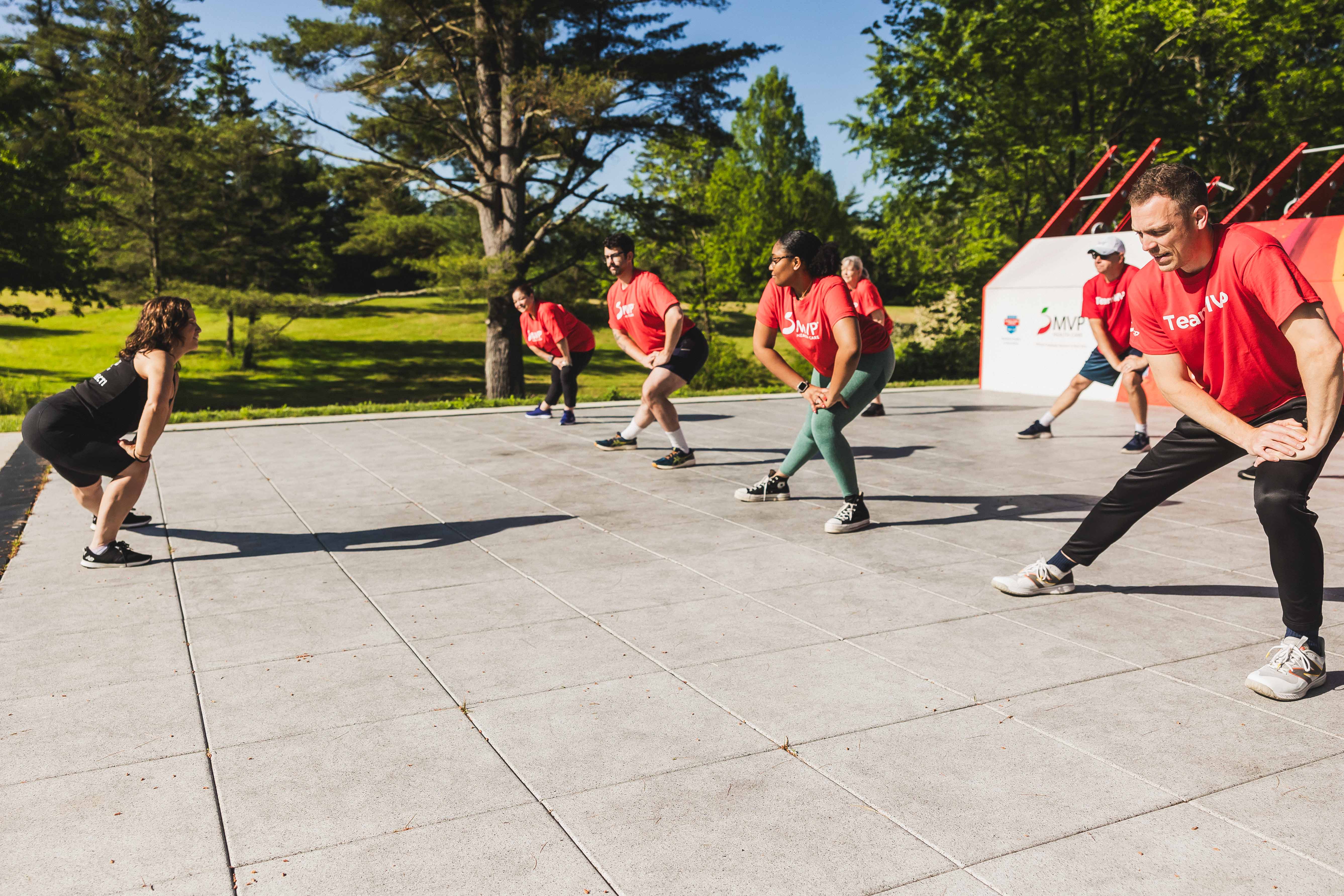 Many people doing group work out on outdoor sport court.