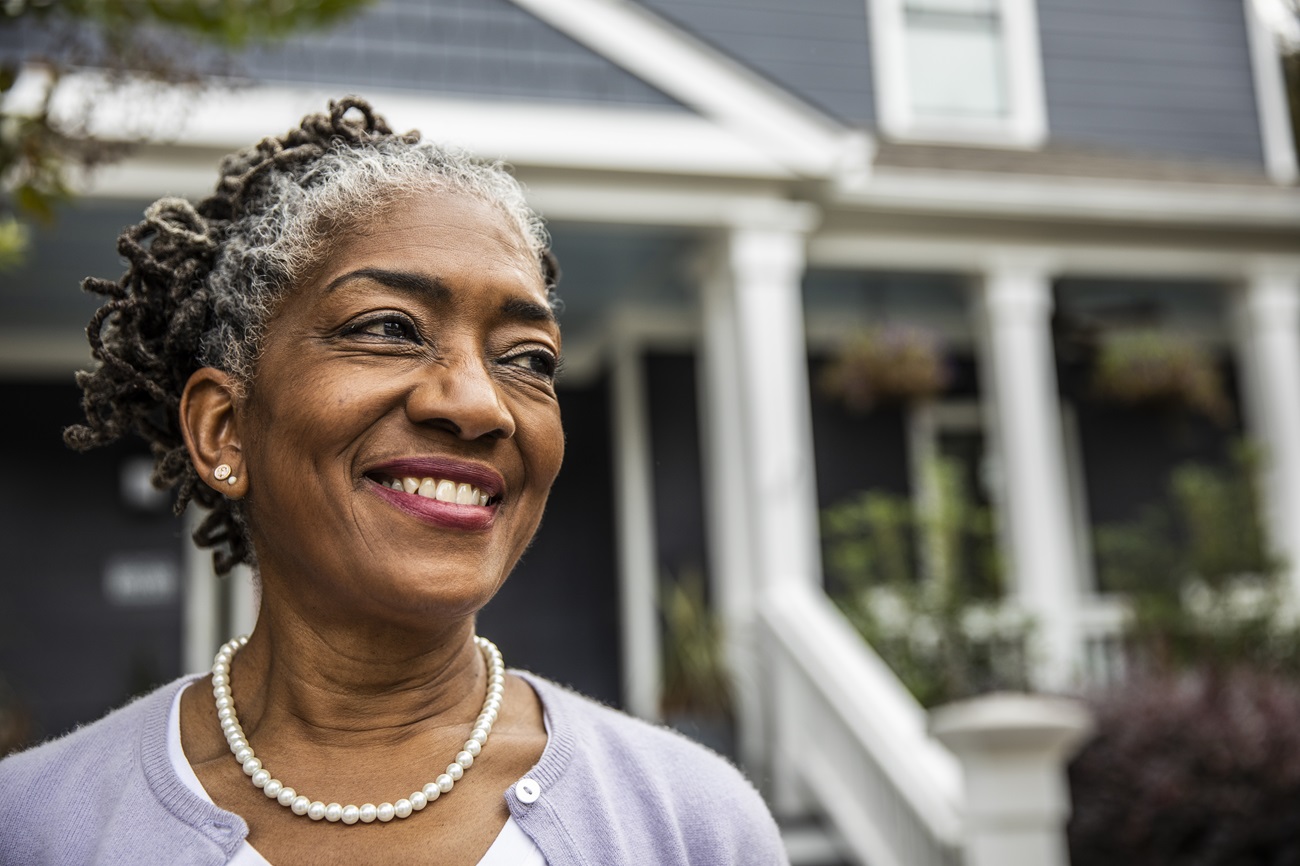 smiling-medicare-aged-woman Woman outside her home