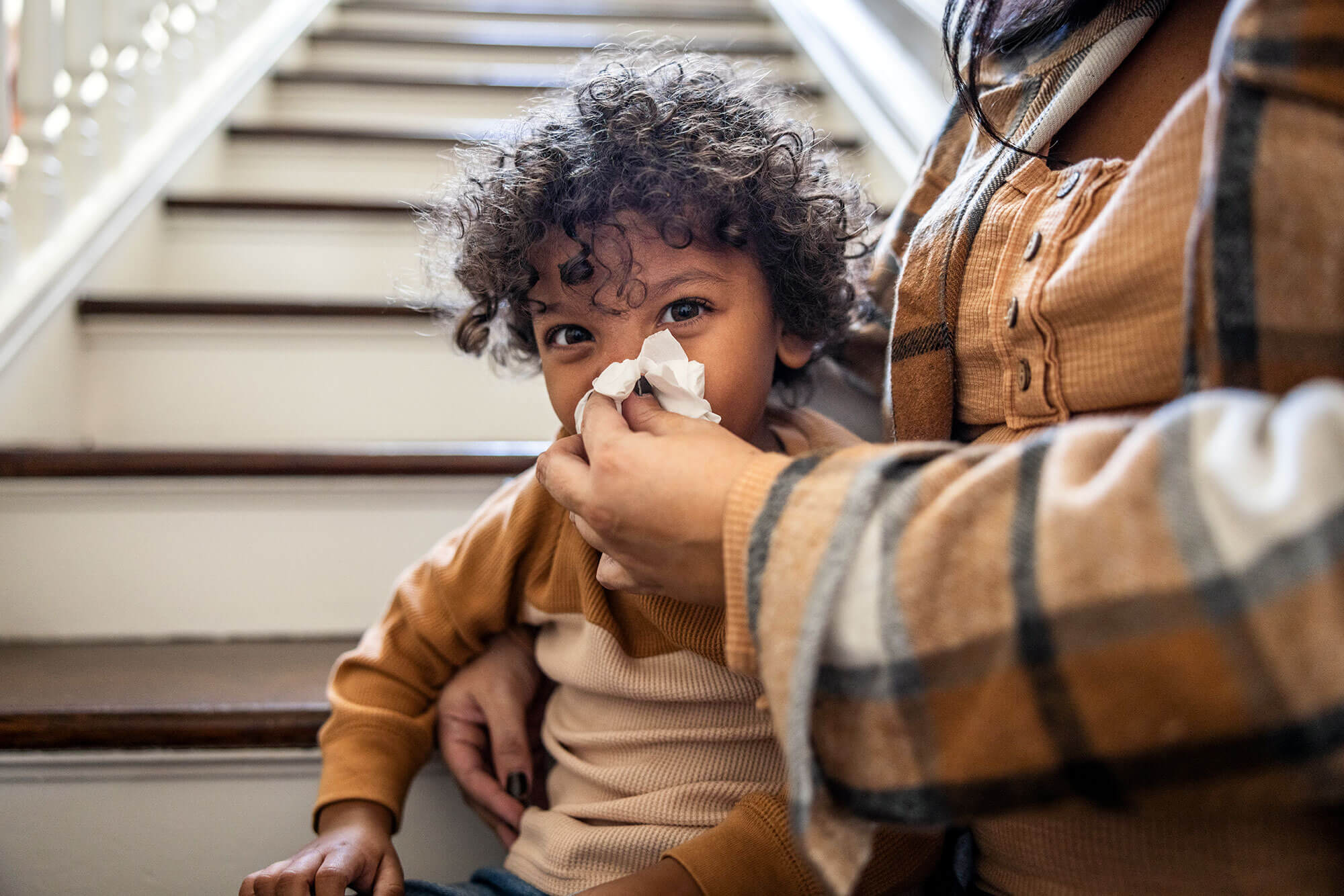 a little boy whose mother is wiping his nose with a tissue