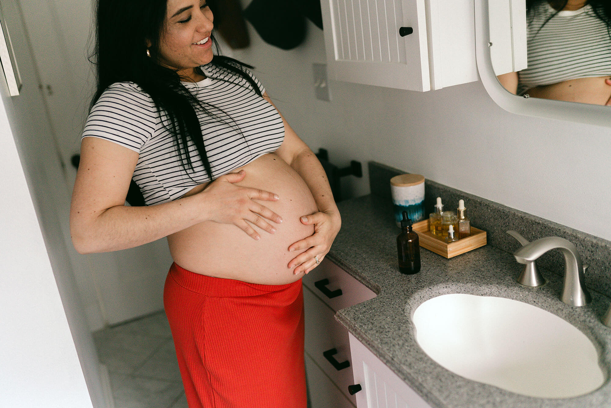 A pregnant woman looking at herself in the mirror in a bathroom